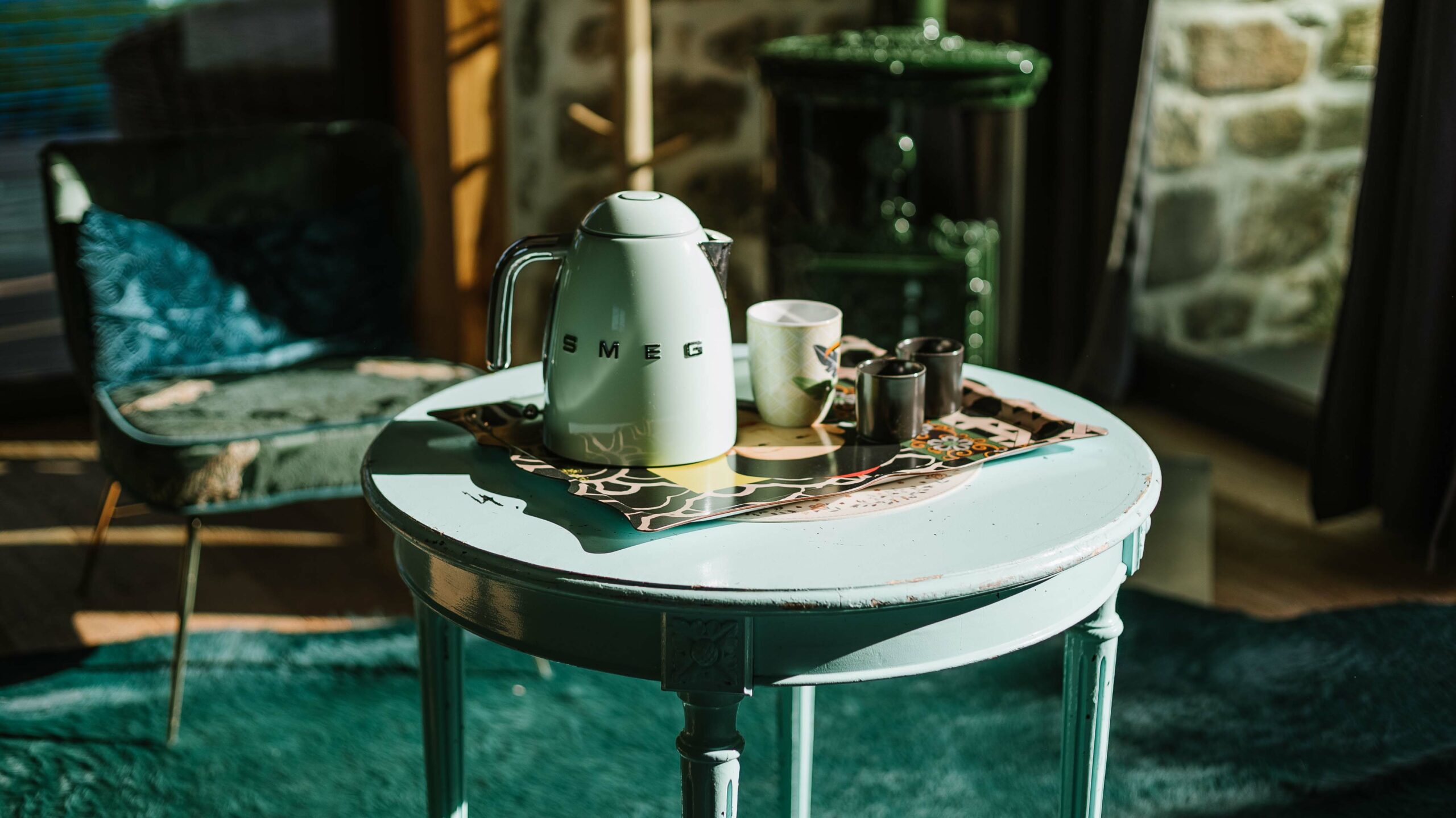 Une bouillore smeg vert pastel posée sur une table avec son thé